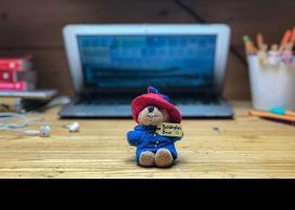Paddington bea plushy in front of laptop