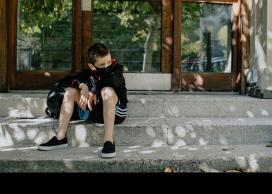 Student sitting on sidewalk